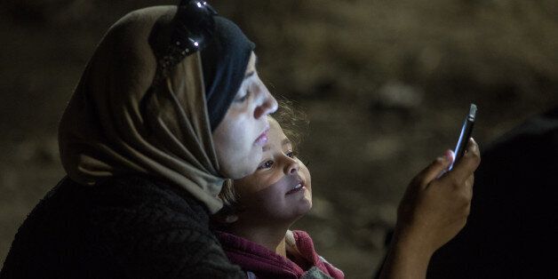 헝가리 국경지대 로즈케에서 한 소녀가 엄마의 휴대폰 화면을 들여다보고 있다.