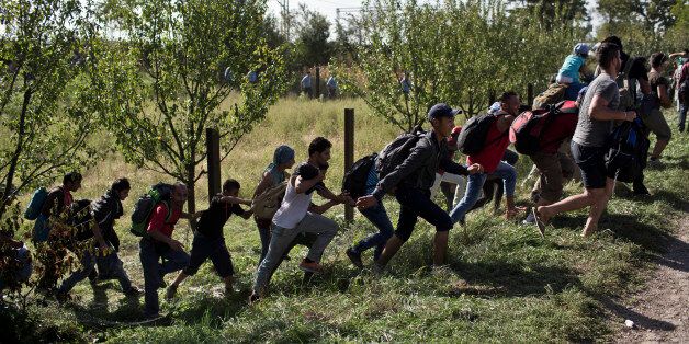 People run amid scuffles with the Croatian police in Tovarnik, Croatia, Thursday, Sept. 17, 2015. Hundreds of migrants have pushed through police lines in the eastern Croatian town of Tovarnik,  with people trampling and falling on each other amid the chaos, as more than 2,000 men, women and children were stuck at the local train station for hours in blazing heat and sun on Thursday, waiting to board trains and buses for transport to refugee centers. (AP Photo/Marko Drobnjakovic)