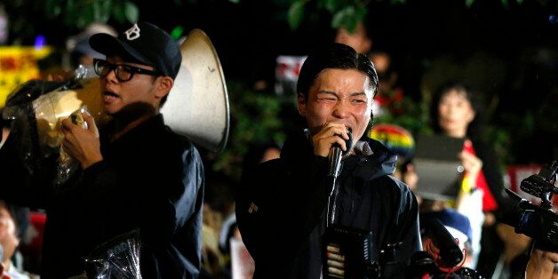 Aki Okuda, center, a leader of the student group known as SEALDs, or Students Emergency Action for Liberal Democracies, shouts slogans during a rally against Japanese government in front of the parliament building in Tokyo, Friday, Sept. 18, 2015. Japan's parliament is moving toward final approval of legislation that would loosen post-World War II constraints placed on its military, an issue that has sparked sizeable street protests and raised fundamental questions about whether the nation needs