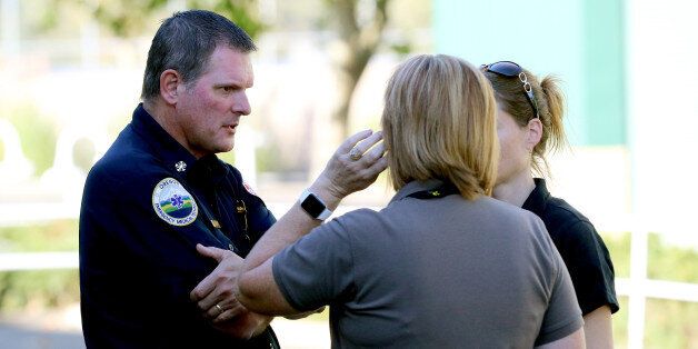 An Oregon Emergency Medical Technician, left, speaks with others at the county fairgrounds in Roseburg, Ore., Thursday, Oct. 1, 2015, following a deadly shooting at nearby Umpqua Community College. Students and faculty were bused to the fairgrounds where counselors were available and some parents waited for their children. (AP Photo/Ryan Kang)
