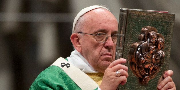 Pope Francis raises the book of the Gospels as he celebrates the opening Mass of the Synod of bishops, in St. Peter's Basilica at the Vatican, Sunday, Oct. 4, 2015. (AP Photo/Alessandra Tarantino)