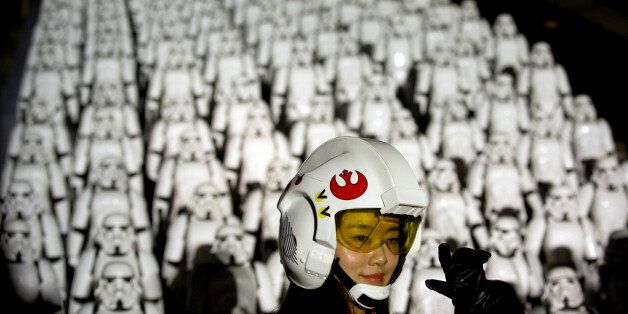 A Chinese Star Wars fan dressed in costume poses for a photo in front of hundreds of miniature storm trooper figures placed atop the Juyongguan section of the Great Wall of China during a promotional event for the movie