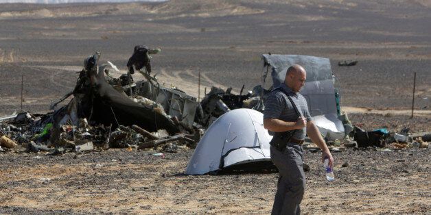 A Russian investigator walks near wreckage a day after a passenger jet bound for St. Petersburg, Russia, crashed in Hassana, Egypt, on Sunday, Nov. 1, 2015. The Metrojet plane, bound for St. Petersburg in Russia, crashed 23 minutes after it took off from Egypt's Red Sea resort of Sharm el-Sheikh on Saturday morning. The 224 people on board, all Russian except for four Ukrainians and one Belarusian, died. (AP Photo/Amr Nabil)