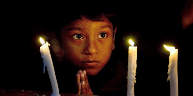 A Christian boy prays during a candlelight vigil for victims who were killed in Friday's attacks in Paris, at St. Thomas Church in Islamabad, Pakistan, Sunday, Nov. 15, 2015. Multiple attacks across Paris on Friday night have left scores dead and hundreds injured. (AP Photo/Anjum Naveed)
