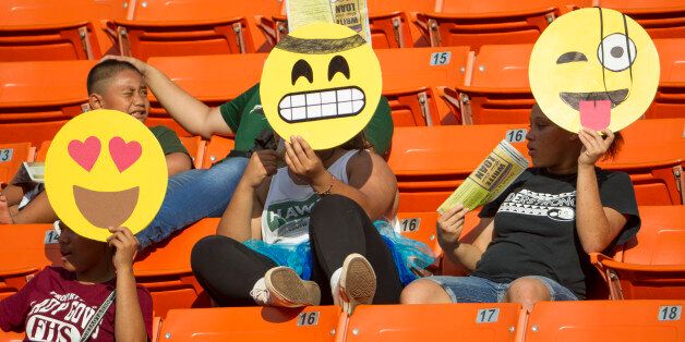 These Hawaii fans hold their emoji character mask in celebration of Halloween before the start of an NCAA college football game between Air Force and Hawaii, Saturday, Oct. 31, 2015, in Honolulu. (AP Photo/Eugene Tanner)
