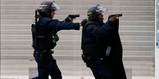 Armed police  operate in Saint-Denis, a northern suburb of Paris, Wednesday, Nov. 18, 2015. Police say two suspects in last week's Paris attacks, a man and a woman, have been killed in a police operation north of the capital. Two police officers have been injured in the standoff. Police have said the operation is targeting the suspected mastermind of last week's attacks, believed to be holed up in an apartment in Saint-Denis with several other heavily armed suspects. (AP Photo/Francois Mori)
