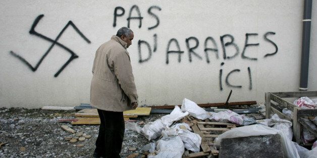 A Muslim resident stands by racial slurs painted on the walls of a mosque in the town of Saint-Etienne, central France, Monday Feb.8, 2010. The French Council of the Muslim Faith says such vandalism has multiplied in France