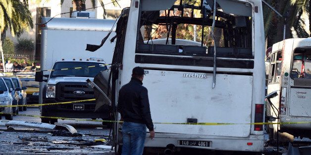 A plainclothes police officer walks beside the bus that exploded Tuesday in Tunis, Wednesday Nov.25, 2015. Tunisia's Interior Ministry says 10 kilograms (22 pounds) of military explosives were used in an attack on a bus carrying presidential guards that left at least 13 people dead. (AP Photo)
