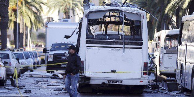 A man walks past the bus that exploded Tuesday in Tunis, Wednesday Nov.25, 2015.  Tunisia's president declared a 30-day state of emergency across the country and imposed an overnight curfew for the capital Tuesday after an explosion struck a bus carrying members of the presidential guard, killing at least 12 people and wounding 20 others. (AP Photo)