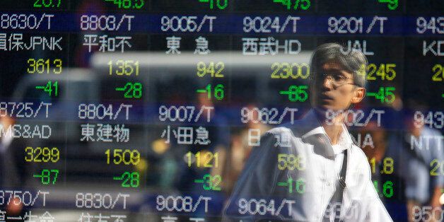 A man is reflected on an electronic stock indicator of a securities firm in Tokyo, Wednesday, Oct. 14, 2015.  Asian stock markets extended losses Wednesday following a drop on Wall Street as investors digested weak Chinese trade data and China's low inflation rate.(AP Photo/Shizuo Kambayashi)