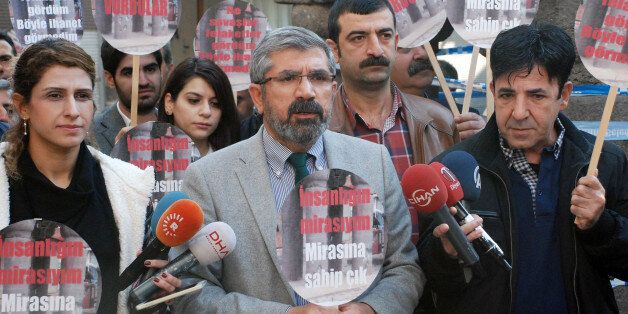Tahir Elci, the head of Diyarbakir Bar Association, speaks to the media shortly before being killed in Diyarbakir, Turkey, Saturday, Nov. 28, 2015. Elci, a prominent lawyer, who faced a prison term on charges of supporting Turkey's Kurdish rebels, has been killed in an attack in Diyarbakir. Elci was shot on Saturday while he was making a press statement in front of a historical mosques damaged during fightings between Kurdish rebels and security forces. Elci holds a placard that reads: