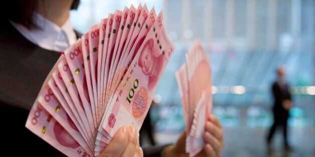 A staff member displays the new version of the 100-yuan RMB banknotes for photographers at the Bank of China Tower in Hong Kong, Thursday, Nov. 12, 2015. China released Thursday a new version of the 100-yuan bill, which bears a golden