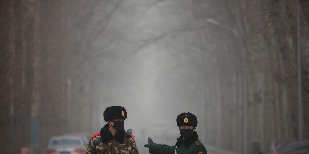Chinese paramilitary policemen stop a car from entering a blocked-off road in an embassy district in Beijing, Friday, Dec. 25, 2015. Security remained elevated in parts of Beijing on Friday, a day after the U.S. and other foreign embassies in China warned of potential threats to Westerners around the Christmas holiday. (AP Photo/Mark Schiefelbein)