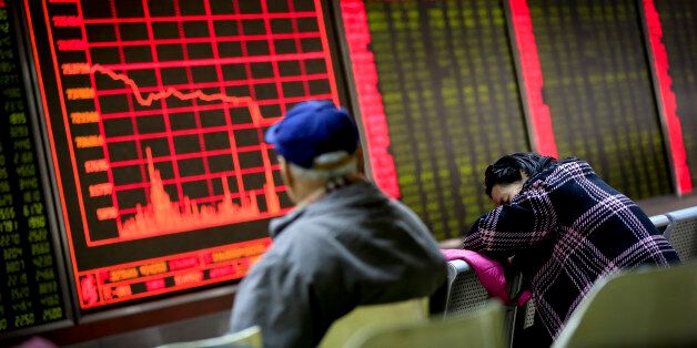 A woman takes a nap as a man looks at an electronic board displaying stock prices at a brokerage house in Beijing, Monday, Jan. 4, 2016. Shanghai's stock index plunged nearly 7 percent on Monday, sparking a halt in trading of Chinese shares, after weak manufacturing data and Middle East tensions weighed on Asian markets. (AP Photo/Andy Wong)