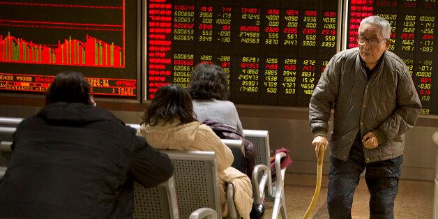 A Chinese investor walks through a brokerage house in Beijing, Friday, Dec. 4, 2015. Asian stocks sank Friday, extending a sell-off in world markets after Europe's central bank unveiled plans to stimulate the continent's ailing economy that fell short of investor expectations. (AP Photo/Mark Schiefelbein)