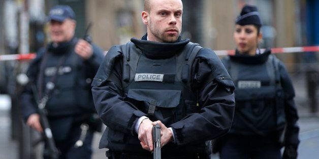 Police officers secure the perimeter near the scene of a fatal shooting which took place at a police station in Paris, Wednesday, Jan. 7, 2016. French officials say a man armed with a knife was shot to death by officers at a police station in northern Paris. Two officials say the man had wires extending from his clothing, and an explosives squad is on site. (AP Photo/Christophe Ena)