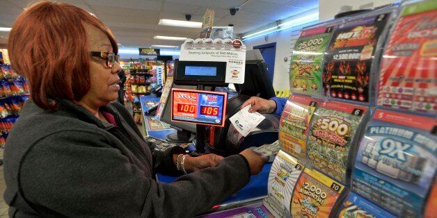 In this Oct. 23, 2015 photo, Vera Washington of Chicago, buys lotto tickets at the K&D Marathon station in Hammond, Ind. With Illinois delaying payouts over $600 because of its budget mess, neighboring states are salivating at the chance to boost sales. Businesses near borders, particularly in Indiana, Kentucky and Iowa, say theyâve already noticed a difference. The Lottery problems stemming from Illinoisâ budget impasse have led to a lawsuit and come amid questions about Illinois reve