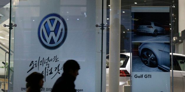 People walk by a logo of Volkswagen at a dealership in Seoul, South Korea, Thursday, Nov. 26, 2015.  South Korea said Thursday it fined Volkswagen $12.3 million and ordered recalls of 125,522 diesel vehicles after the government found their emissions tests were rigged. (AP Photo/Ahn Young-joon)