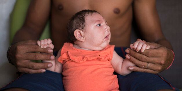 In this Dec. 23, 2015 photo, Dejailson Arruda holds his daughter Luiza at their house in Santa Cruz do Capibaribe, Pernambuco state, Brazil. Luiza was born in October with a rare condition, known as microcephaly. Luiza's mother Angelica Pereira was infected with the Zika virus after a mosquito bite. Brazilian health authorities are convinced that Luiza's condition is related to the Zika virus that infected her mother during pregnancy. (AP Photo/Felipe Dana)