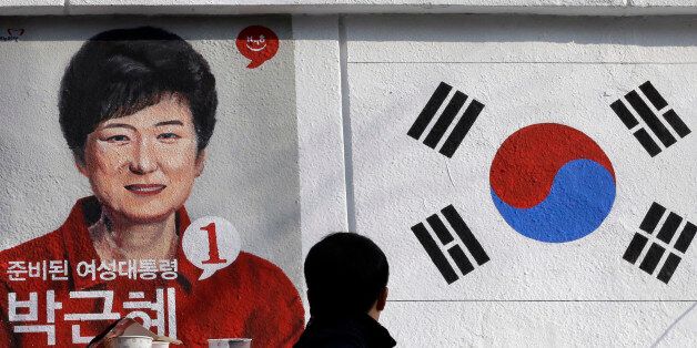 A man looks at the wall paintings of South Korea's President-elect Park Geun-hye of ruling Saenuri Party and national flag at Korean Civic Education Institute for Democracy in Seoul, South Korea, Thursday, Dec. 20, 2012. The wall painting is part of renovation work for the building as well as publicizing the 18th Presidential Election which elected Park as the country's first female president. (AP Photo/Lee Jin-man)