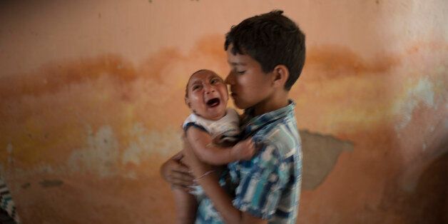 FILE - In this Dec. 23, 2015, file photo, 10-year-old Elison nurses his 2-month-old brother Jose Wesley, who was born with microcephaly, at their house in Poco Fundo, Pernambuco state, Brazil. The U.S. Centers for Disease Control and Prevention said Wednesday, Jan. 13, 2016, that it has found the strongest evidence so far of a possible link between a mosquito-borne virus and a surge of birth defects in Brazil. (AP Photo/Felipe Dana, File)