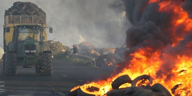 French Farmers block the RN12 road near Guingamp, western France, Friday, Jan. 22, 2016.  About 60 tractors and about 200 farmers took part in Fridayâs protest, among several the farmers have carried out after, they say the French government has done little to help. The farmers want more help from the government, saying they cannot pay off their expenses because prices have stagnated or fallen while they face higher expenses than their competitors elsewhere in the European Union. (AP Photo/