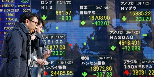 People walk past an electronic stock indicator of a securities firm showing global stock shares including Japan's Nikkei 225, top center, that lost 2.4 percent to 16,708.90, in Tokyo, Tuesday, Jan. 26, 2016. Asian stock markets sank Tuesday, led by a plunge in the Shanghai index, after a renewed slump in the price of oil kept investors on edge about the global economy. (AP Photo/Shizuo Kambayashi)