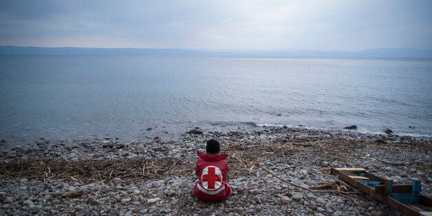 A member of the Greek Red Cross waits for migrants and refugees to arrive on a beach of the Greek island of Lesbos Tuesday, Jan. 26, 2016. More than 850,000 people, most fleeing conflict in Syria and Afghanistan, entered Greece by sea in 2015, according to the UNHCR, and already in 2016, some 35,455 people have arrived despite plunging winter temperatures.(AP Photo/Mstyslav Chernov)