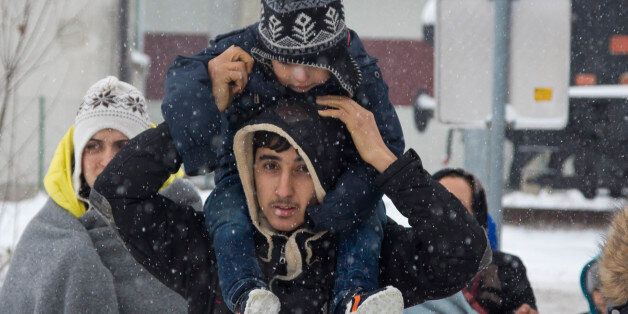 A group of migrants move through snow towards a train station to be transferred to Austria, near the border with Croatia, in Dobova, Slovenia, Sunday, Jan. 3, 2016. (AP Photo/Darko Bandic)