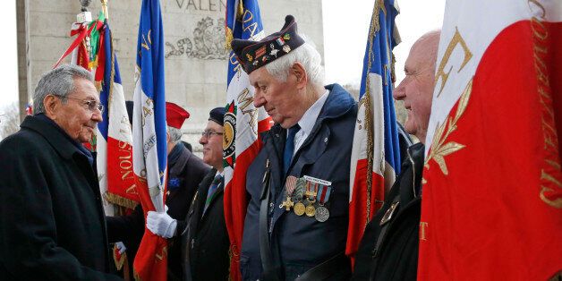 Cuba's President Raul Castro, left, shakes hands with war veterans during a ceremony at the Tomb of the Unknown Soldier at the Arc de Triomphe in Paris, Monday,  Feb. 1, 2016. Raul Castro is paying a state visit to France, in the first European foray by a Cuban leader in two decades, as Cuba opens up its economy. (Jacky Naegelen/Pool photo via AP)
