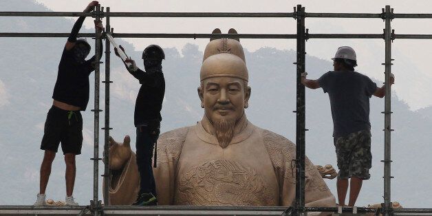 Construction workers set up a stage in front of a statue of Chosun Dynasty's King Sejong for public viewing for the 2014 Brazil World Cup, in Seoul, South Korea, Tuesday, June 17, 2014. South Korea will play Russia, Belgium and Algeria in the World Cup soccer tournament. (AP Photo/Ahn Young-joon)
