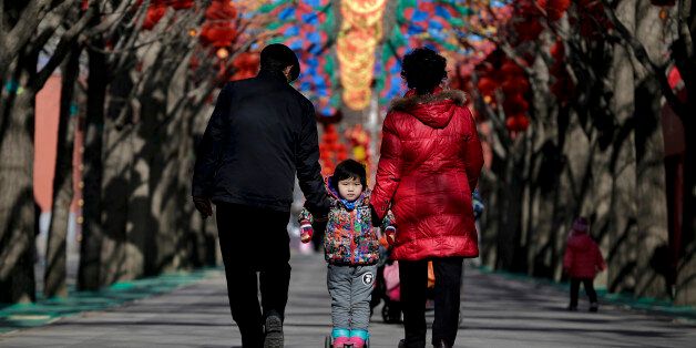 A Chinese elderly couple holds a child standing on a scooter as they walk under colorful decorations for a temple fair ahead of the Chinese Lunar New Year at Ditan Park in Beijing, Tuesday, Feb. 2, 2016. Chinese will celebrate the Lunar New Year on Feb. 8 this year which marks the Year of Monkey on the Chinese zodiac. (AP Photo/Andy Wong)
