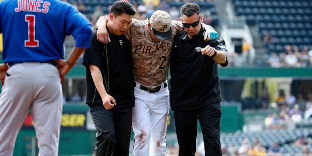Pittsburgh Pirates' Jung Ho Kang, center, is helped off the field by  team trainer, right, and his interpreter after injuring his left leg turning a double play in the first inning of a baseball game against the Chicago Cubs in Pittsburgh, Thursday, Sept. 17, 2015. Kang left the game. (AP Photo/Gene J. Puskar)