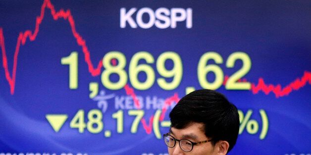 A currency trader walks by the screen showing the Korea Composite Stock Price Index (KOSPI) at the foreign exchange dealing room in Seoul, South Korea, Thursday, Feb. 11, 2016. Asian stocks shuddered again Thursday, led by sharp drops in Hong Kong and South Korea, which were catching up to global market turmoil after being shut for Lunar New Year holidays.(AP Photo/Lee Jin-man)