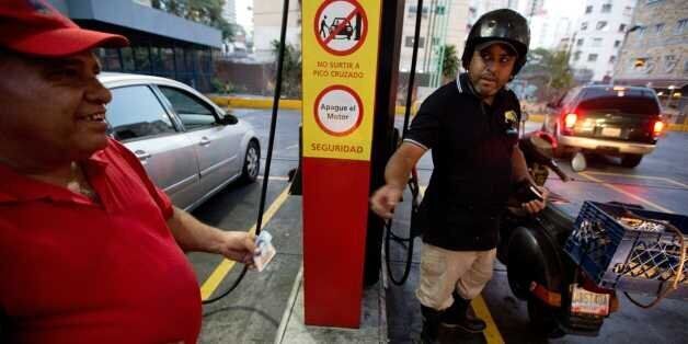 A motorcyclist pays about two Bolivars (3 cents of a dollar) after filling his scooter's tank at a gas station in Caracas, Venezuela, Wednesday, Feb. 17, 2016. Venezuelaâs government is raising gasoline prices sixtyfold, the first increase of any kind in more than 17 years as the country struggles with an economic collapse. Yet drivers will still be able to fill their tanks for pennies. (AP Photo/Fernando Llano)