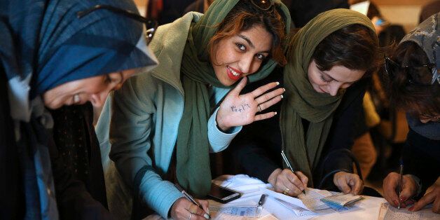 An Iranian woman displays her ink-stained finger after voting in the parliamentary and Experts Assembly elections at a polling station in Qom, 125 kilometers (78 miles) south of the capital Tehran, Iran, Friday, Feb. 26, 2016.  Polls opened Friday in Iran's parliamentary elections, the country's first since its landmark nuclear deal with world powers last summer. (AP Photo/Ebrahim Noroozi)