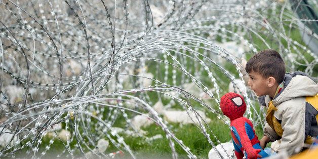A boy plays with a Spiderman doll next to the razor wire around the fence between Greece and Macedonia at the northern Greek border station of Idomeni, Monday, March 7, 2016.  Greek police officials say Macedonian authorities have imposed further restrictions on refugees trying to cross the border, saying only those from cities they consider to be at war can enter as up to 14,000 people are trapped in Idomeni, while another 6,000-7,000 are being housed in refugee camps around the region.(AP Phot
