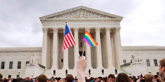 FILE - In this June 26, 2015 file photo, a man holds a U.S. and a rainbow flag outside the Supreme Court in Washington after the court legalized gay marriage nationwide. (AP Photo/Jacquelyn Martin, File)