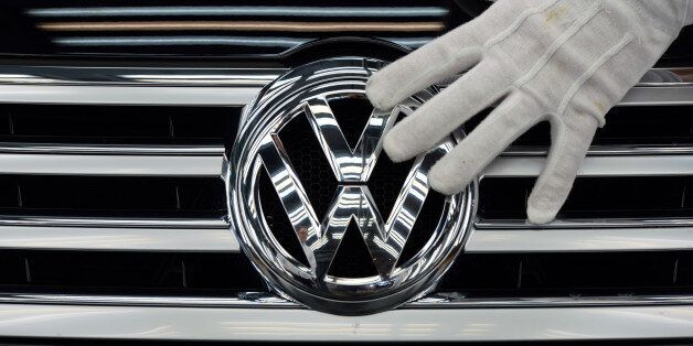 FILE -  In this Oct. 23, 2015 file photo a worker touches the logo of Volkswagen AG on a Phaeton in Dresden, Germany. Volkswagen is reporting a loss of 1.67 billion euros (US dollar 1.83 billion) in the third quarter, Wednesday, Oct. 28, 2015, as earnings took a hit from 6.7 billion euros in set-asides for recalls and fines connected to cars rigged to evade U.S. diesel emissions testing. (Ralf Hirschberger/dpa via AP, file)