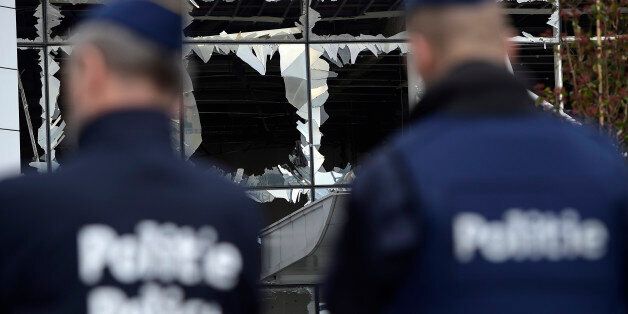 Two police officers stand in front of blown out windows at Zaventem Airport in Brussels on Wednesday, March 23, 2016. Belgian authorities were searching Wednesday for a top suspect in the country's deadliest attacks in decades, as the European Union's capital awoke under guard and with limited public transport after scores were killed and injured in bombings on the Brussels airport and a subway station. (AP Photo/Yorick Jansens, Pool photo via AP)