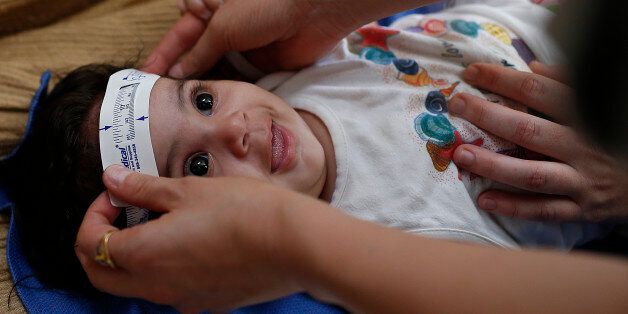Three-month-old Esther Kamilly has her head measured by Brazilian and U.S. health workers from the United States' Centers for Disease Control and Prevention (CDC) at her home in Joao Pessoa, Brazil, Wednesday, Feb. 24, 2016, as part of a study to determine if the Zika virus is causing babies to be born with a birth defect affecting the brain. Their goal is to persuade about 100 mothers of infants recently born with the defect as well to enroll in the study. They also need participation as contro