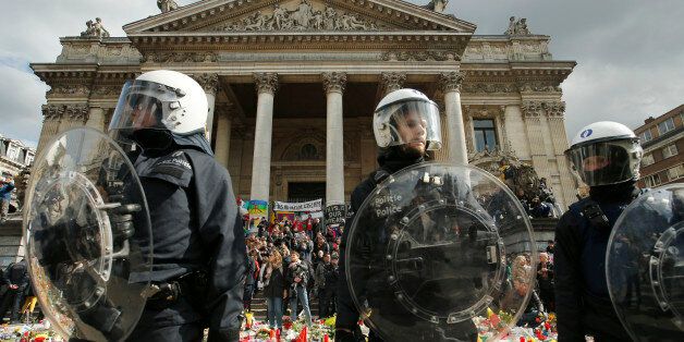 Police in riot gear protect one of the memorials to the victims of the recent Brussels attacks, a right wing demonstrators  protest near the Place de la Bourse in Brussels, Sunday, March, 27, 2016.  In a sign of the tensions in the Belgian capital and the way security services are stretched across the country, Belgium's interior minister appealed to residents not to march Sunday in Brussels in solidarity with the victims.