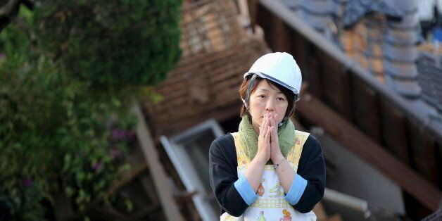 A woman reacts in front of collapsed house caused by an earthquake in Mashiki town, Kumamoto prefecture, southern Japan, in this photo taken by Kyodo April 16, 2016.  Mandatory credit REUTERS/Kyodo ATTENTION EDITORS - FOR EDITORIAL USE ONLY. NOT FOR SALE FOR MARKETING OR ADVERTISING CAMPAIGNS. THIS IMAGE HAS BEEN SUPPLIED BY A THIRD PARTY. IT IS DISTRIBUTED, EXACTLY AS RECEIVED BY REUTERS, AS A SERVICE TO CLIENTS. MANDATORY CREDIT. JAPAN OUT. NO COMMERCIAL OR EDITORIAL SALES IN JAPAN.      TPX I