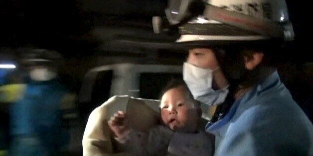 An eight-month-old baby is carried away by a rescue worker after being rescued from her collapsed home caused by an earthquake in Mashiki town, Kumamoto prefecture, southern Japan, April 15, 2016 early morning, in this handout still image from a video provided by Kumamoto Prefectural Police.  REUTERS/Kumamoto Prefectural Police/Handout via Reuters  ATTENTION EDITORS - FOR EDITORIAL USE ONLY. NOT FOR SALE FOR MARKETING OR ADVERTISING CAMPAIGNS. NO RESALES. NO ARCHIVE. THIS IMAGE HAS BEEN SUPPLIED