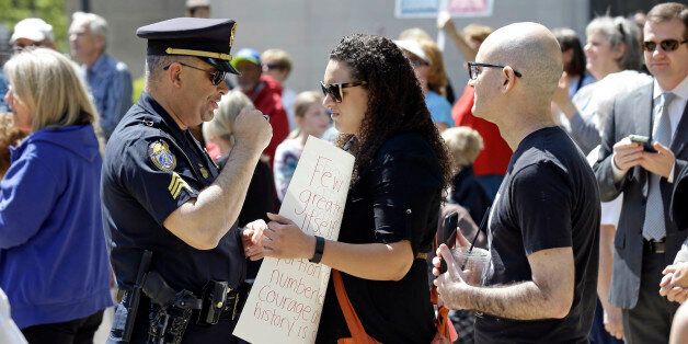 A police officer confronts a lady holding a sign at the North Carolina State Capitol in Raleigh, N.C., Monday, April 11, 2016, during a rally in support of a law that blocks rules allowing transgender people to use the bathroom aligned with their gender identity. (AP Photo/Gerry Broome)