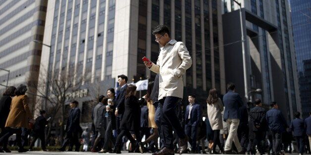A man using his mobile phone walks on a zebra crossing at a business district in Seoul, South Korea, March 23, 2016. Picture taken on March 23, 2016.  REUTERS/Kim Hong-Ji