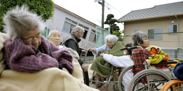 Evacuees from a nursing home wrap themselves in blankets as they take shelter outside their damaged nursing home caused by an earthquake in Mashiki town, Kumamoto prefecture, southern Japan, in this photo taken by Kyodo April 17, 2016. Mandatory credit REUTERS/Kyodo  ATTENTION EDITORS - FOR EDITORIAL USE ONLY. NOT FOR SALE FOR MARKETING OR ADVERTISING CAMPAIGNS. THIS IMAGE HAS BEEN SUPPLIED BY A THIRD PARTY. THIS PICTURE WAS PROCESSED BY REUTERS TO ENHANCE QUALITY. AN UNPROCESSED VERSION WILL BE