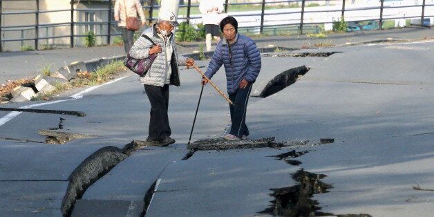 Local residents look at cracks caused by an earthquake on a road in Mashiki town, Kumamoto prefecture, southern Japan, in this photo taken by Kyodo April 16, 2016.  Mandatory credit REUTERS/Kyodo ATTENTION EDITORS - FOR EDITORIAL USE ONLY. NOT FOR SALE FOR MARKETING OR ADVERTISING CAMPAIGNS. MANDATORY CREDIT. JAPAN OUT. NO COMMERCIAL OR EDITORIAL SALES IN JAPAN. THIS IMAGE WAS PROCESSED BY REUTERS TO ENHANCE QUALITY, AN UNPROCESSED VERSION WILL BE PROVIDED SEPARATELY.