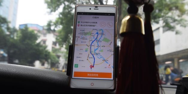 A taxi driver uses the Didi Chuxing app while driving along a street in Guilin, in China's southern Guangxi region on May 13, 2016.Apple has invested 1 billion USD in Chinese ride hailing app Didi Chuxing, the Beijing company said on May 13, as it vies with bitter US-based rival Uber for market share in China. / AFP / GREG BAKER        (Photo credit should read GREG BAKER/AFP/Getty Images)