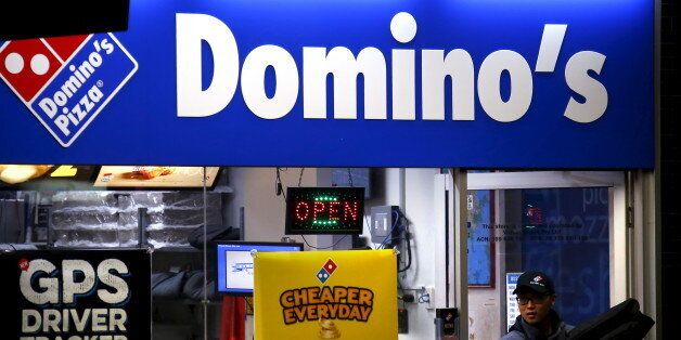 A worker carries a pizza for delivery as he exits a Domino's pizza store in Sydney, Australia, August 12, 2015. Fast food may be falling out of favour in many countries around the world but companies are making healthy profits and boldly innovating in the unlikely market of Australia. Contrary to stereotypes of a beach-going community of fitness fanatics, official data out this week showed 40 percent of Australian adults are dangerously obese and have a poor diet that includes lashings of fast f